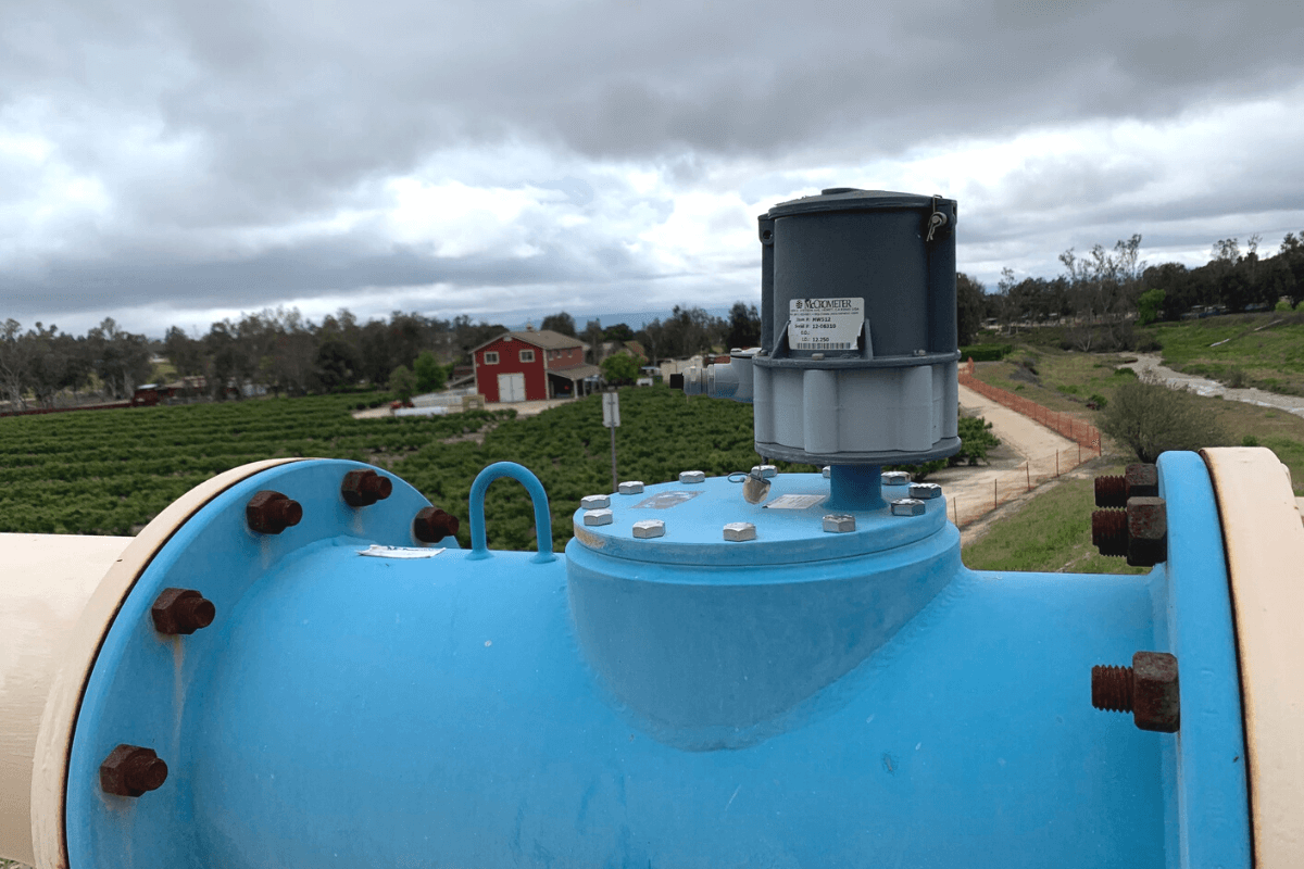 A blue McPropeller flow meter in front of a blueberry farm.