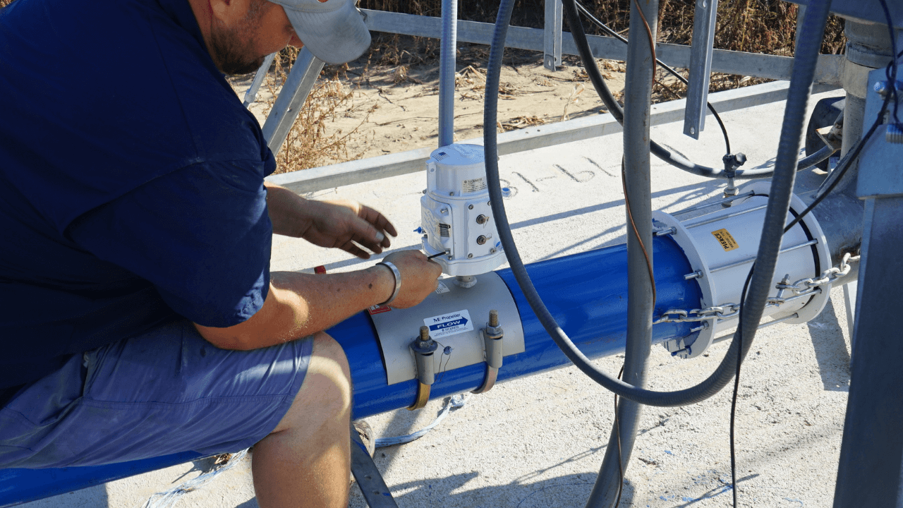 Man working on a blue pipe and flow meter.