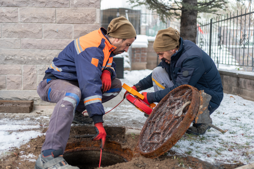Technicians conducting a manhole inspection with a camera.